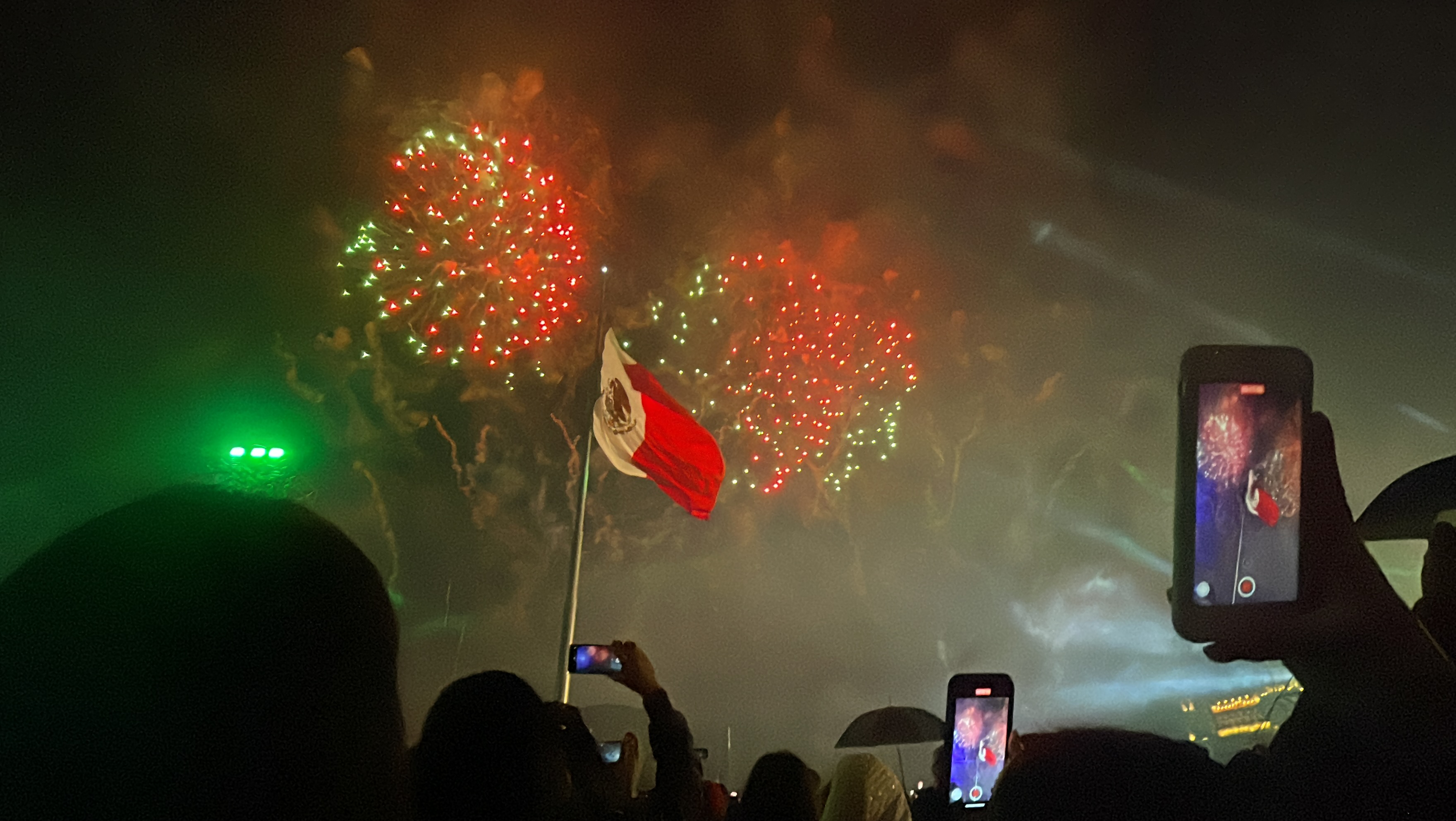 Fireworks explode behind Mexican flag.