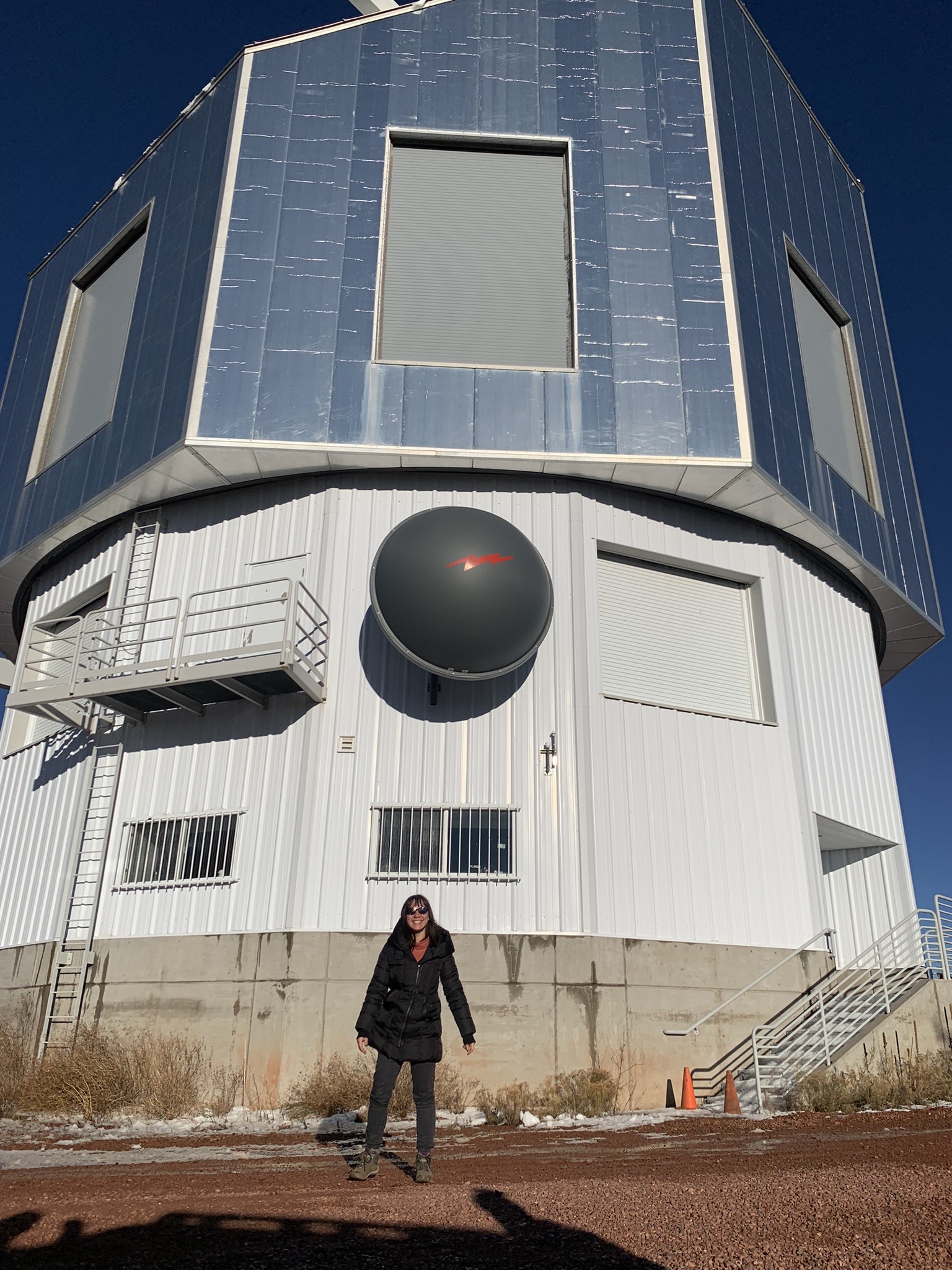 Laura Lee standing in front of a telescope.