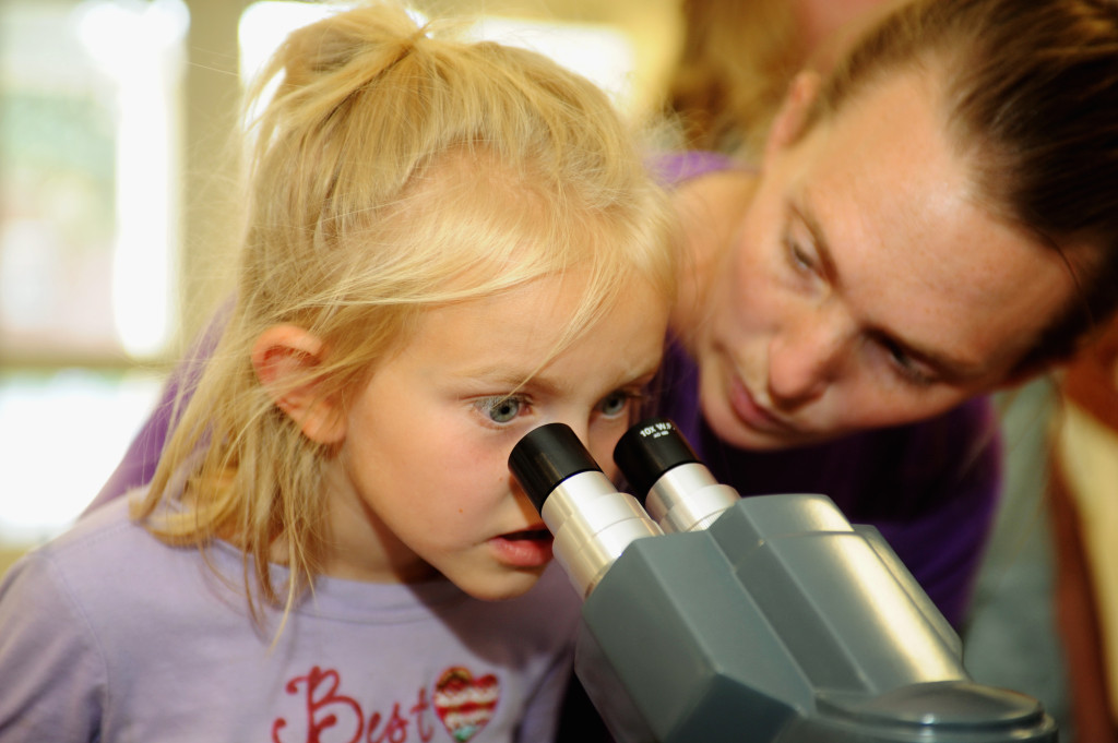 Young girl peering into a microscope