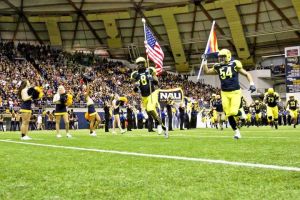 Players hold flags as the NAU football team takes the field