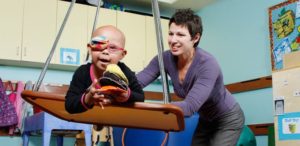 A woman of the occupational therapy program smiles as she tends to a young child