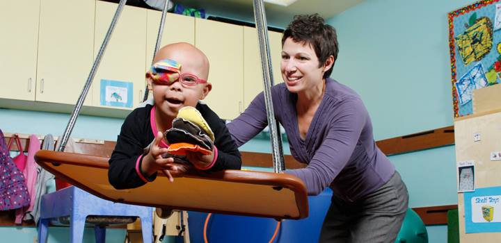 A woman of the occupational therapy program smiles as she tends to a young child