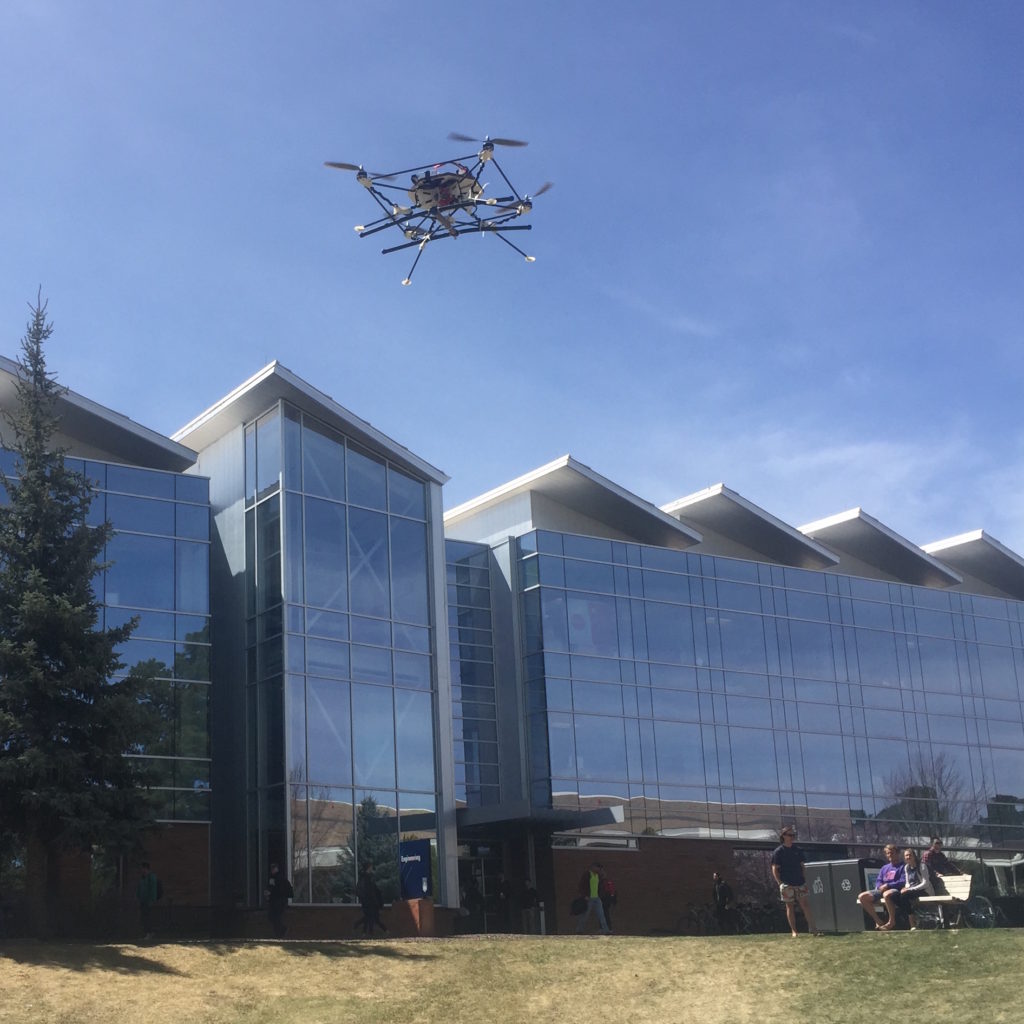 A small drone hovers in front of the engineering building