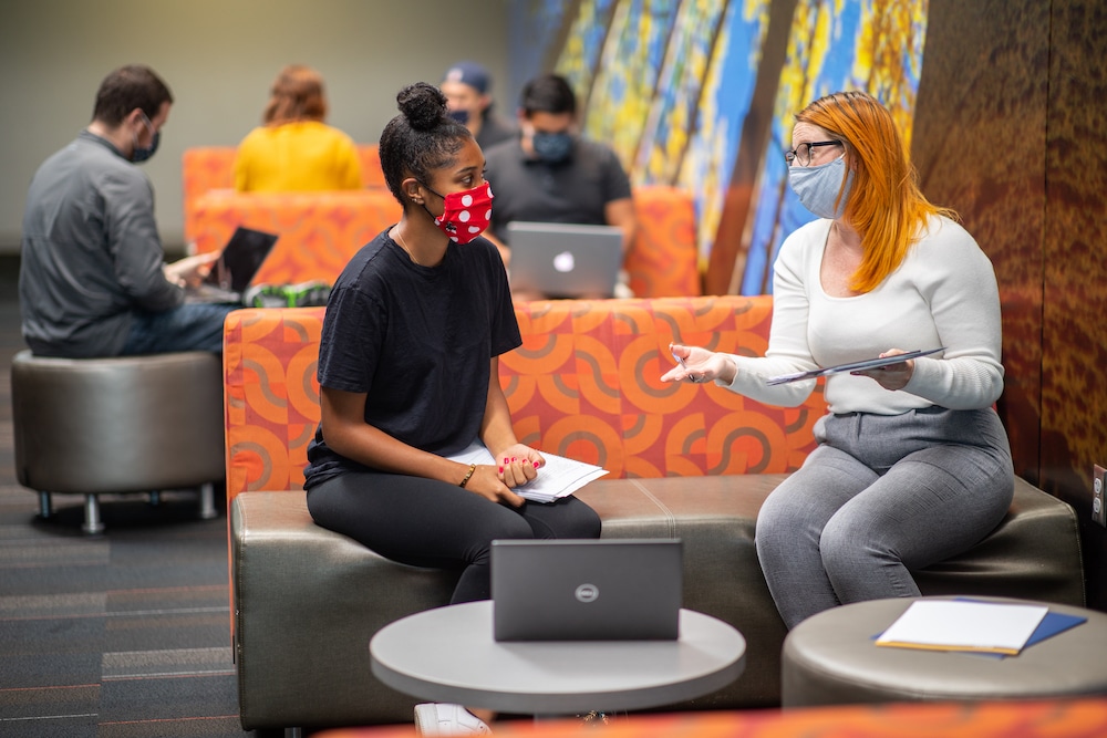 Students sit at tables wearing masks