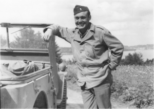 James P. Kuykendall leans against a military vehicle