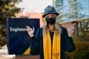 Construction management student in graduation gear with hard hat