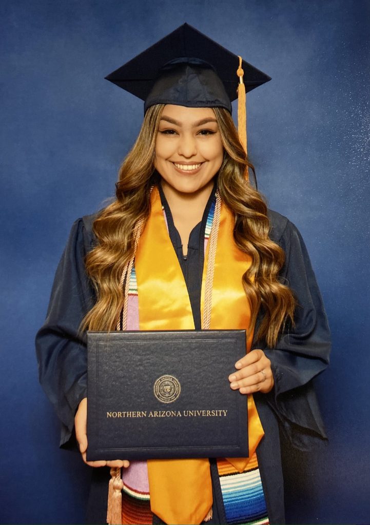 Yasmine Castro Felix holding diploma in graduation attire.