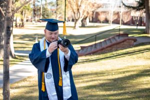 Tuttle in cap and gown looking through camera