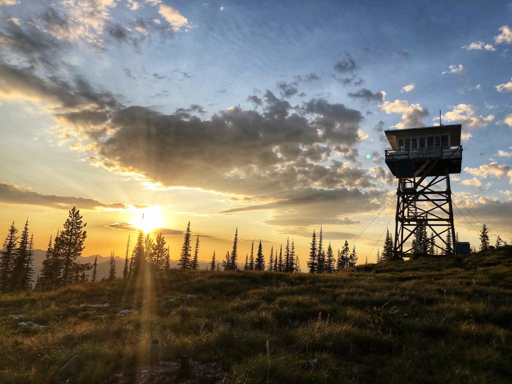 A fire lookout tower at sunset overlooking Flathead Lake in Montana