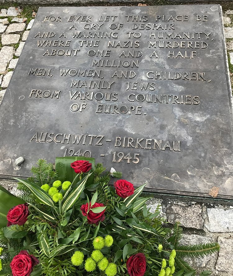 A plaque that reads "For ever let this place be a cry of despair and a warning to humanity, where the Nazis murdered about one and a half million men, women, and children, mainly Jews from various countries of Europe. Auschwitz-Birkenau 1940-1945"
