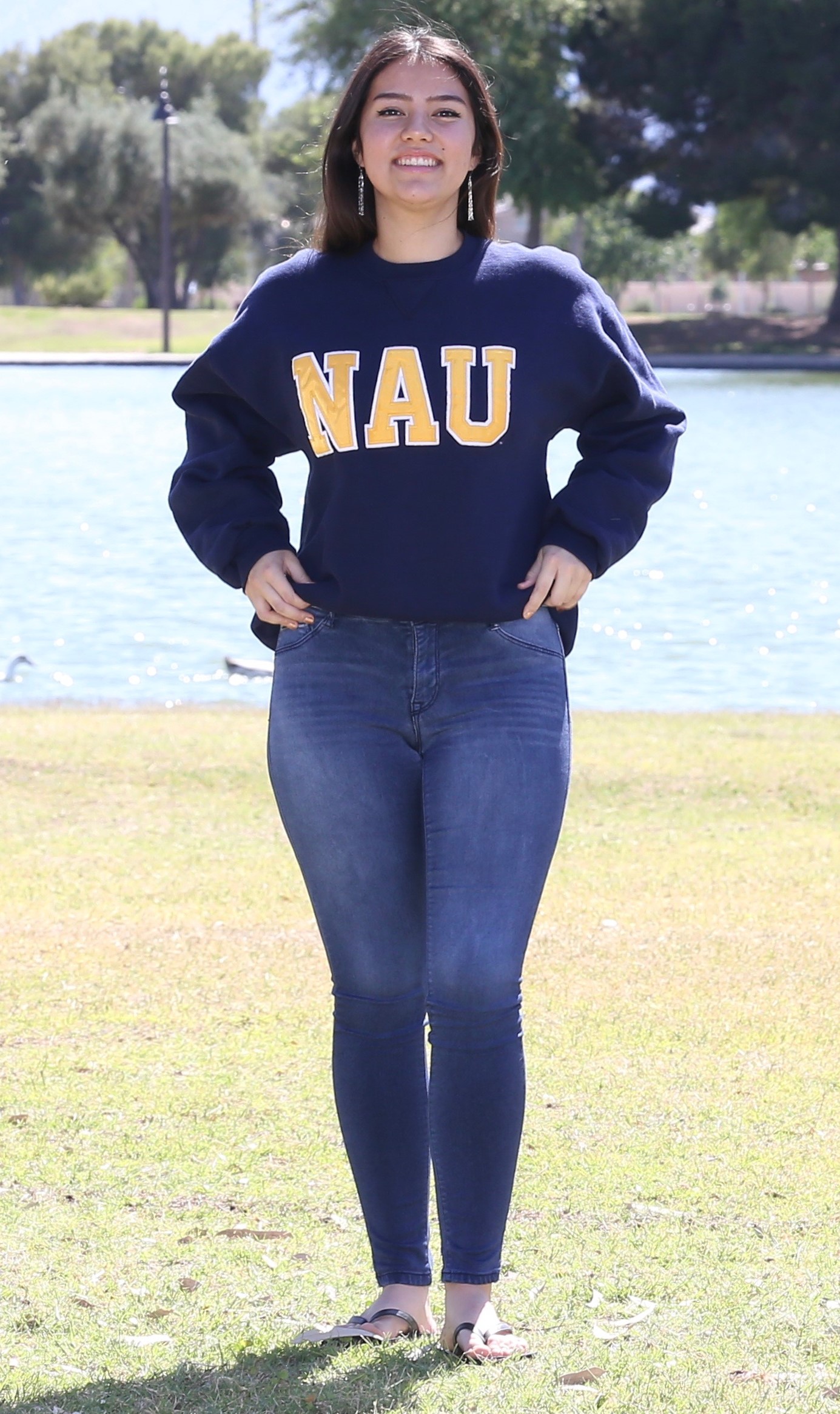Olivia Konig in an NAU sweatshirt in front of a lake