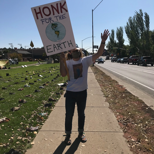 Brendan Trachsel holding a sign that says "honk if you love Earth"