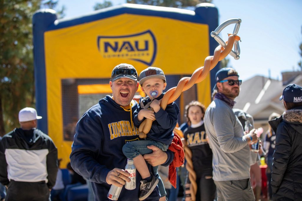 A Lumberjack fan and his young son with a balloon sword smile at the camera.