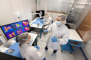 People in cleanroom gear work on space technology