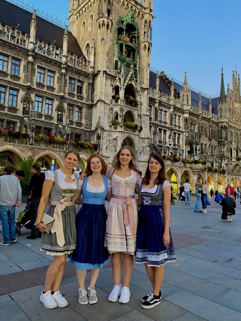 Four women in traditional German dress in front of the Munich City Hall