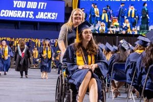 A graduate in a wheelchair returns to her seat after receiving her diploma.