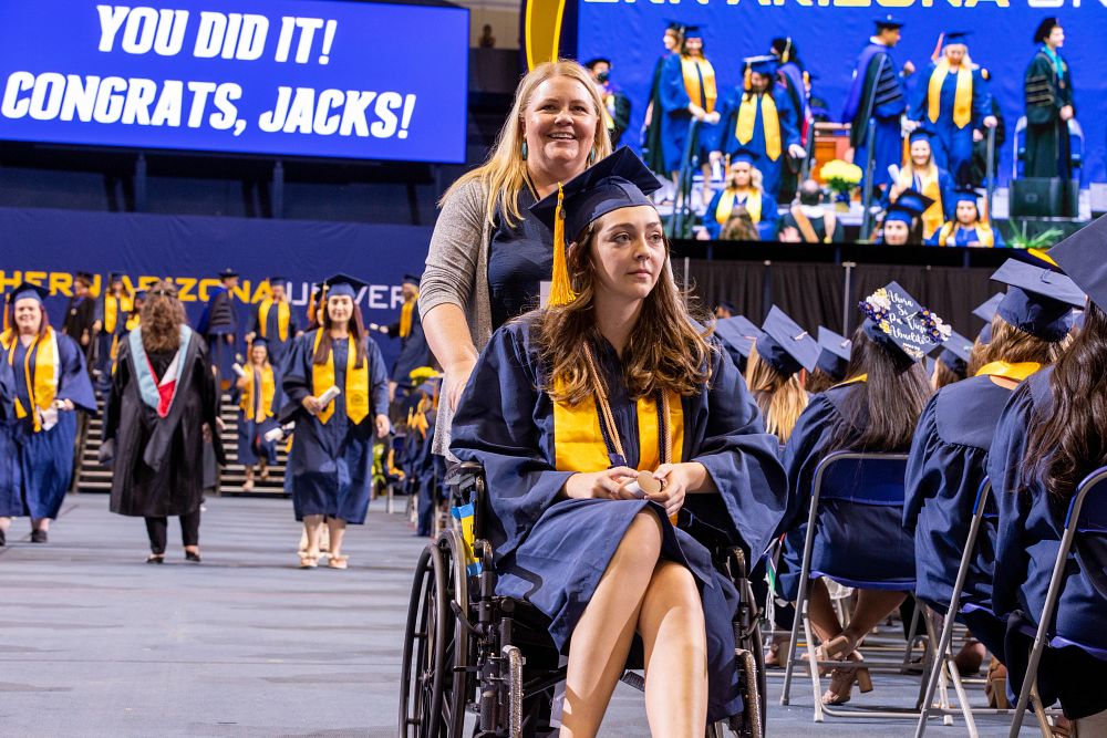 A graduate in a wheelchair returns to her seat after receiving her diploma.