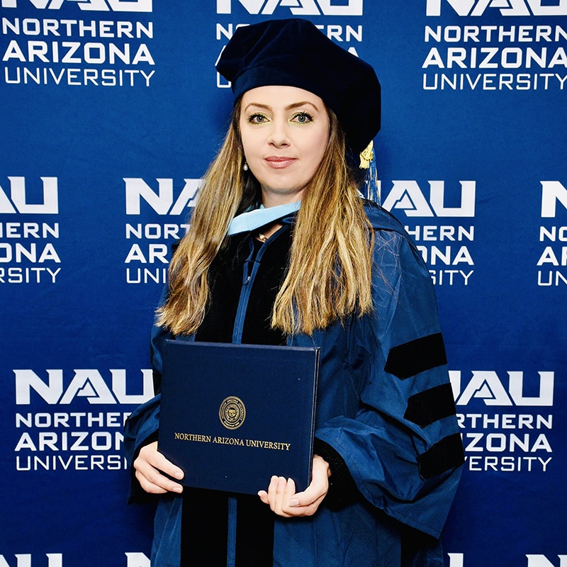 Christina Baciu in her graduation robes holding a diploma