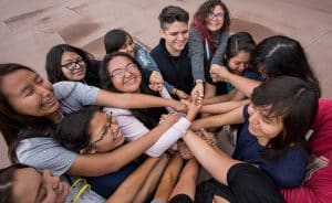 A group of Indigenous students with their hands in the middle.