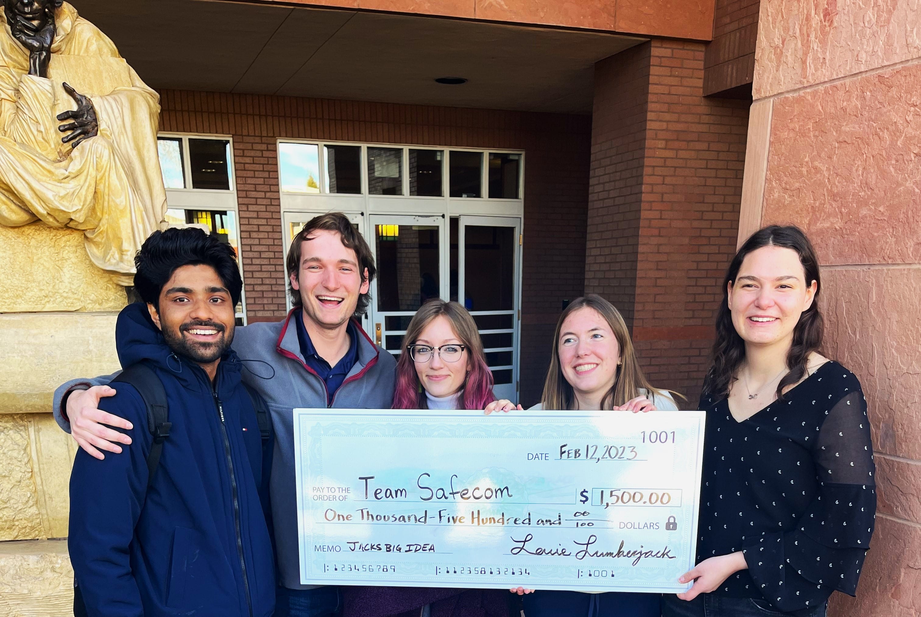 Jacks Big IDEA Winners from left to right: Rohit John, Caden Montesano, Allison Willett-Pishkin, McKinley Burnett, and Alexis Junk holding their big check in front of them standing in fron of Cline Library