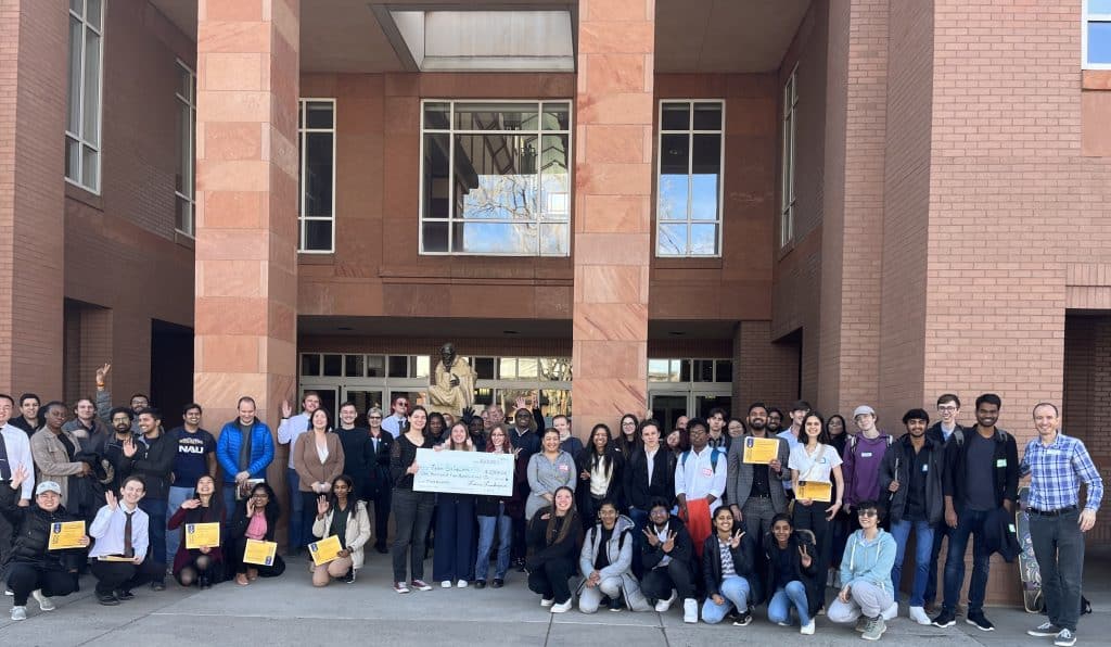 Competitors, judges, and volunteers assembled for a full group photo after the Jacks Big IDEA Competition in front of the Cline library. The winners are holding their big check in the middle of the group.
