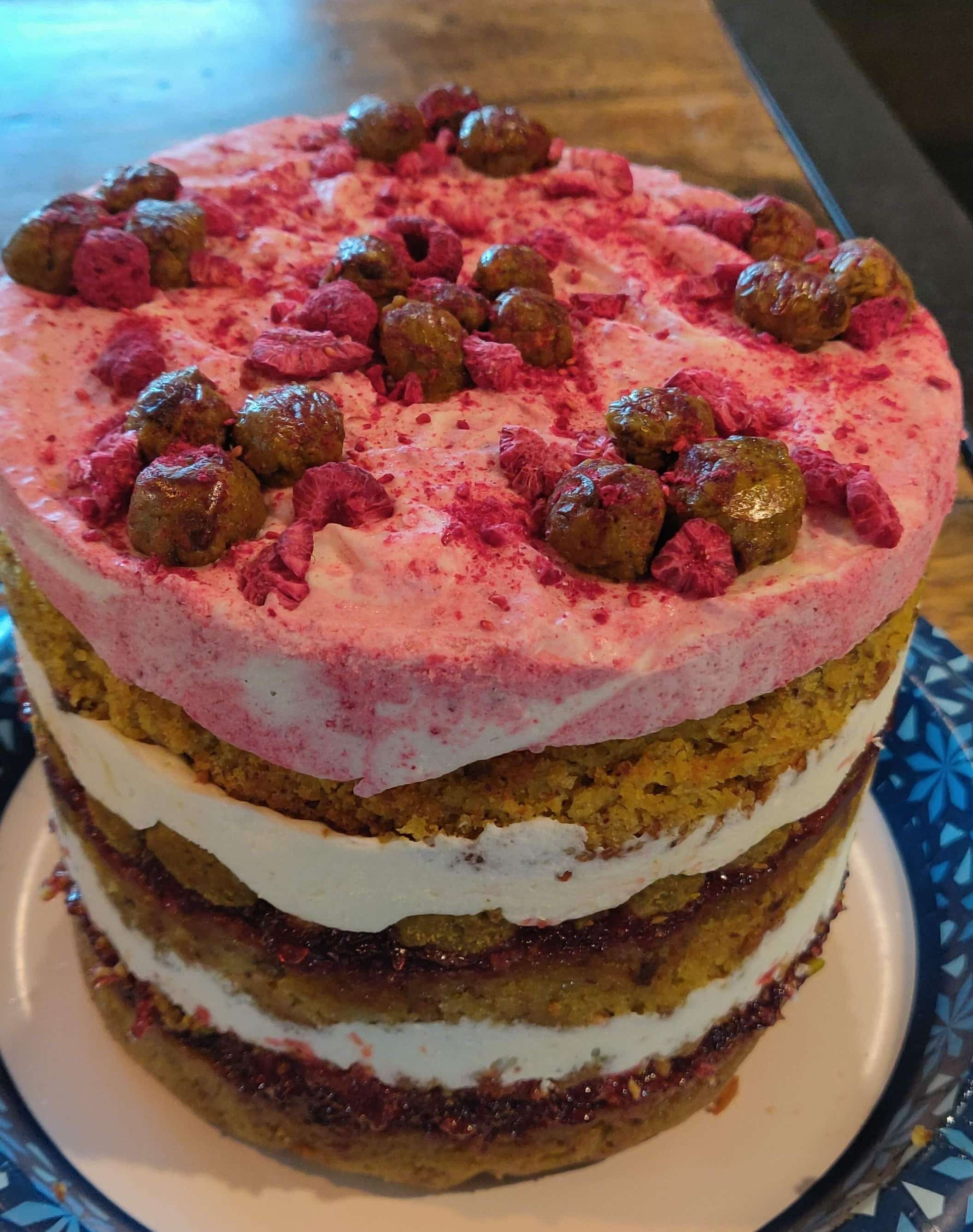 multiple layer pistacio raspberry cake with raspberry pink frosting on top.