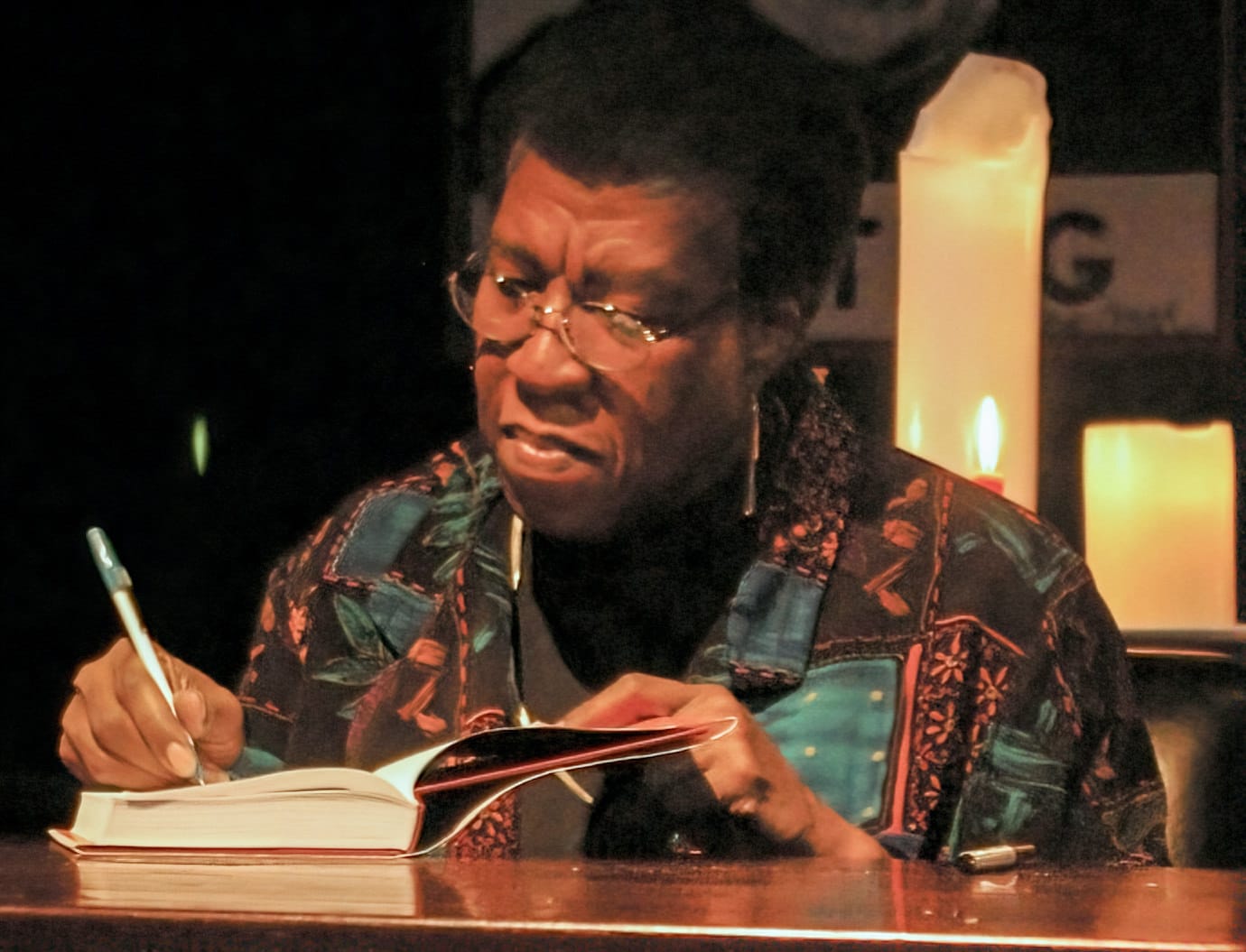 Octavia Estelle Butler wearing glasses signing a copy of ''Fledgling'' 