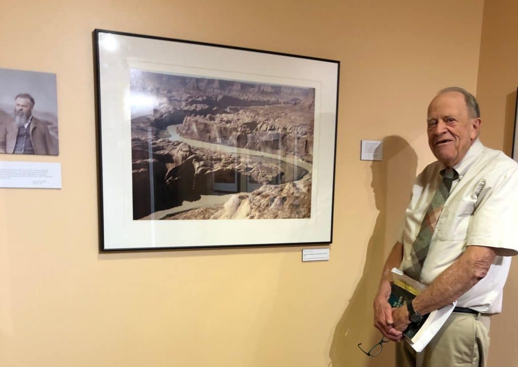 Hank Hassell standing in front of a picture of Glen Canyon in the Lost World exhibit
