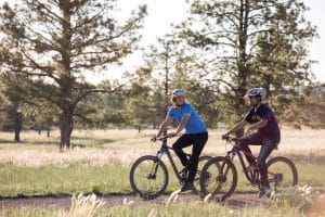 Photo of Two people biking with forest in the background