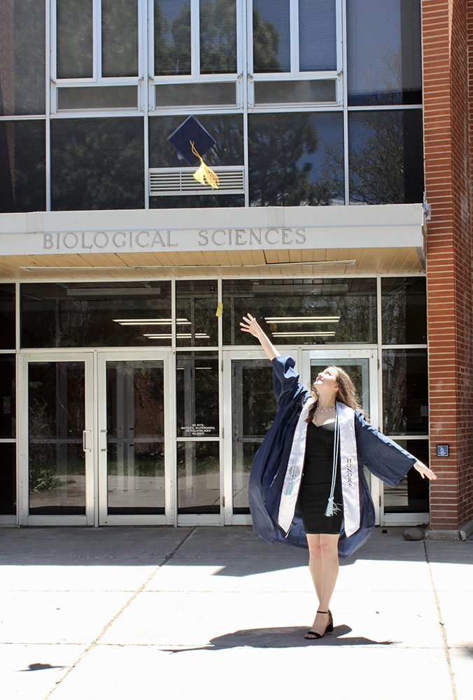 Melissa Briggs throwing her grad cap in the air
