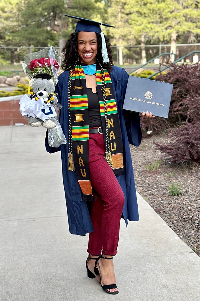 Brianne Kanu in grad gear with her diploma and flowers