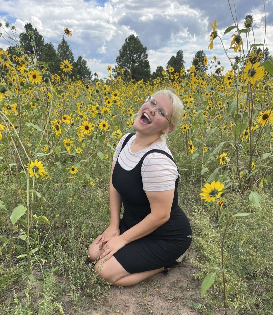 Rebekah Wucinich kneeling in a field of sunflowers