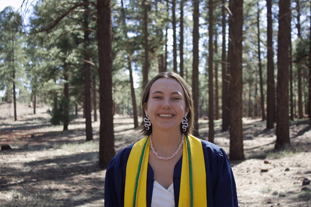 Sophia Swainson in graduation robes in the forest