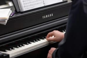 Close-up photo shot of a someone playing the piano. Hands piano and sheet music visible.