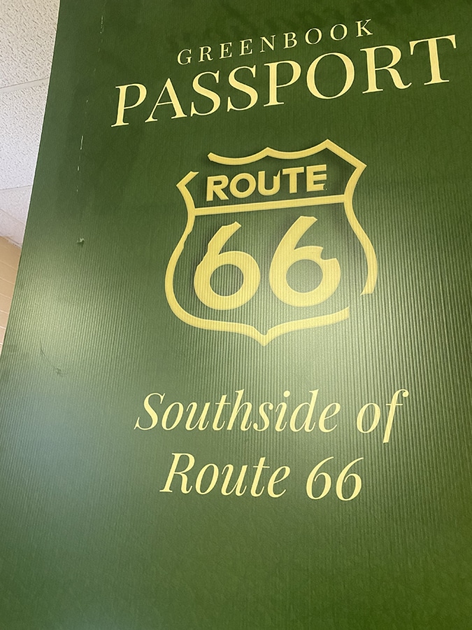 A green poster that says "Greenbook Passport, Route 66, Southside of Route 66"