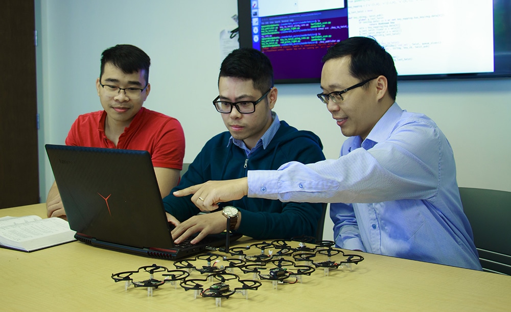 Truong Nghiem and two students work on a laptop.