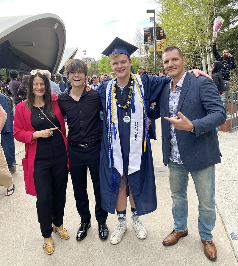 A man in NAU graduation gear with his parents and brother