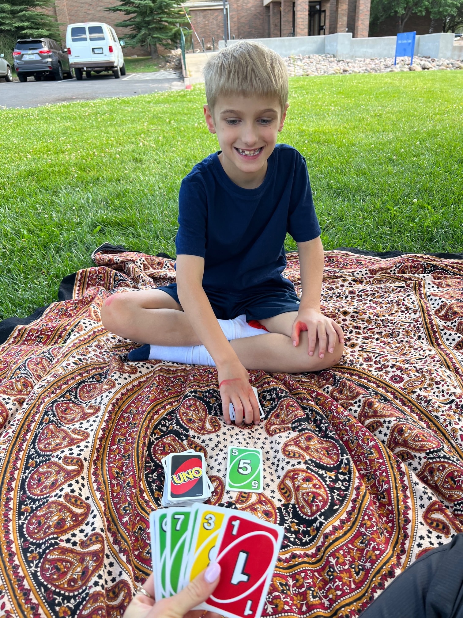 Jayden, a camper at NAU's Camp Chit-Chat, smiling during a game of Uno.