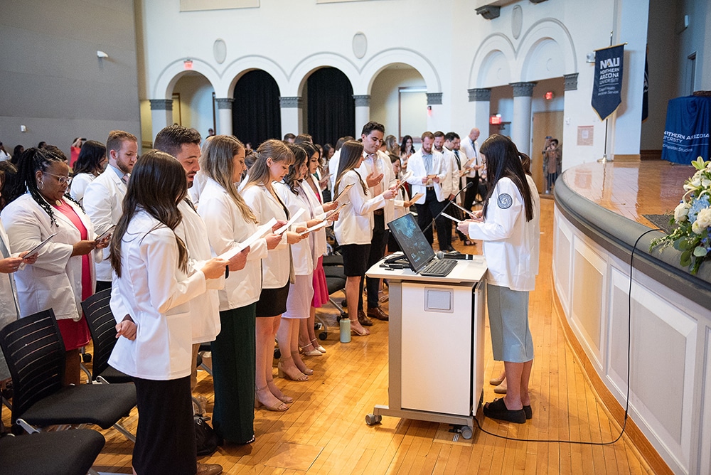 Students in white coats read ano ath from a piece of paper.
