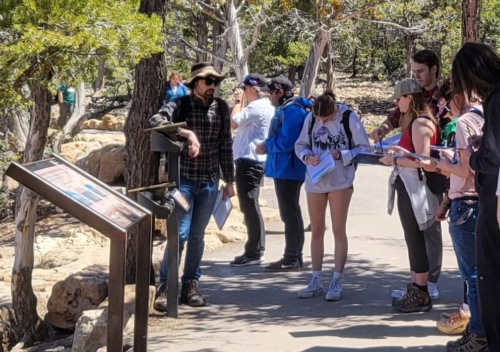 Marrs, in a flannel shirt and hat, talks to students in the Life in the Universe class about the geology of the Grand Canyon.