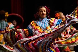 Girl in a colorful hispanic traditional costume dancing.