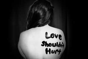 Black and white image of a woman's back that says "Love shouldn't hurt."