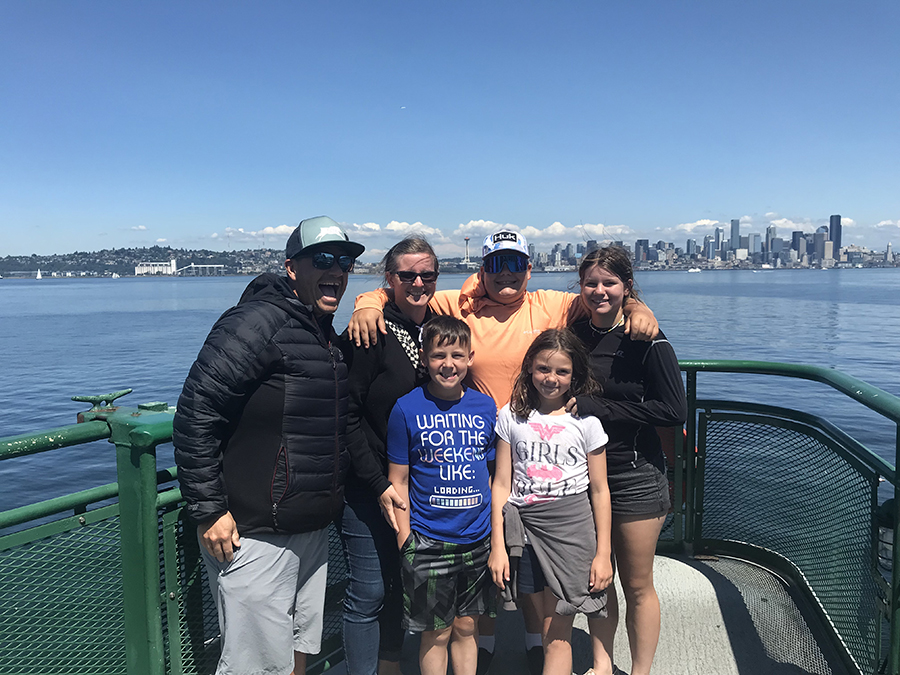 Gabrielle Garcia and her husband and four kids on a boat with a city and blue sky in the background.