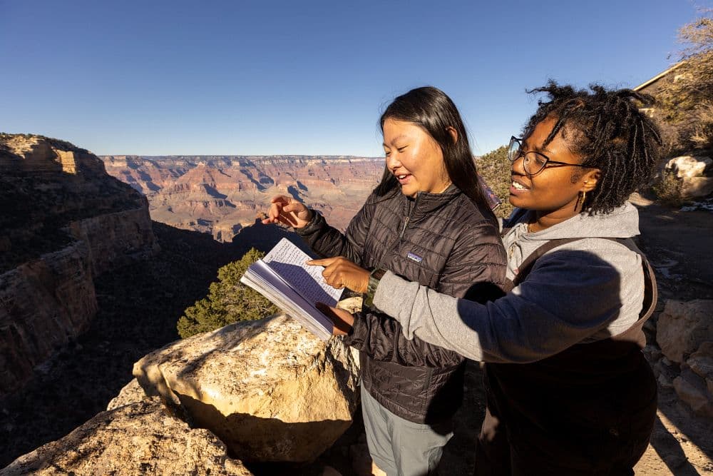Two students talking about their observations of the Grand Canyon with the canyon in the background.