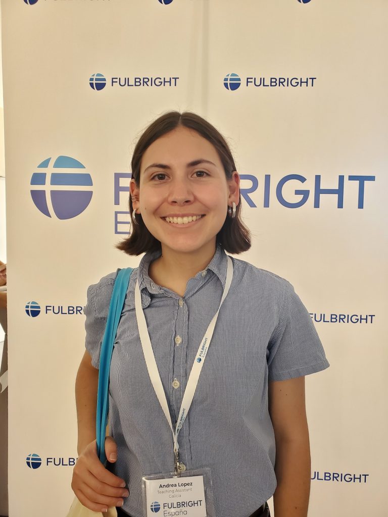 Andrea Lopez posing in front of a Fulbright sign and wearing a nametag