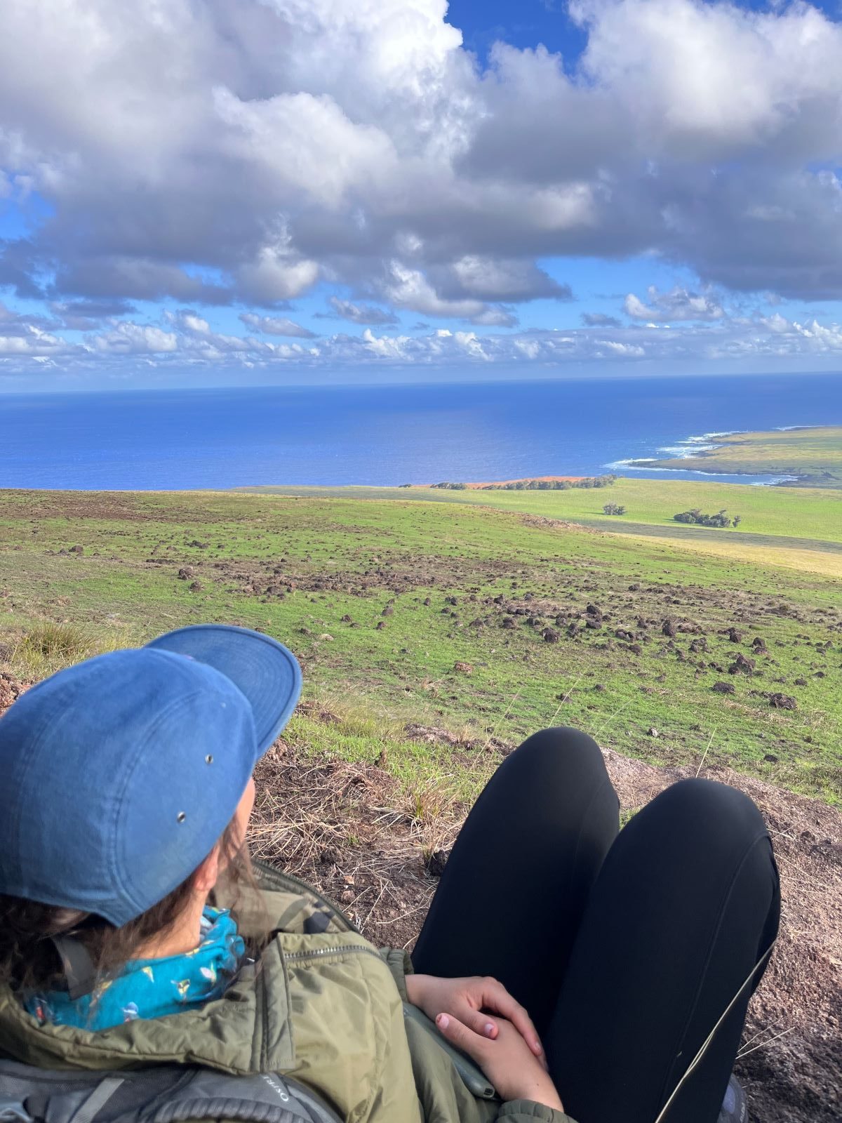 Sydney sitting on the slope of a volcano at Easter Island, looking out at the ocean