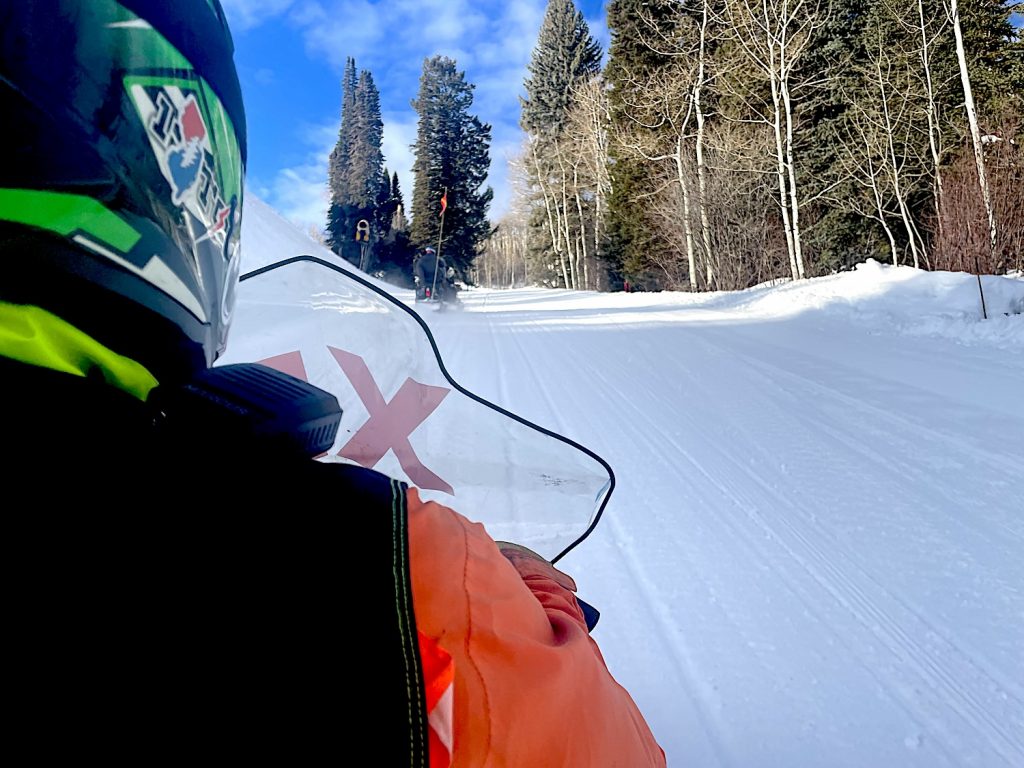 view from the back of a snowbike traveling through a snowy pine forest