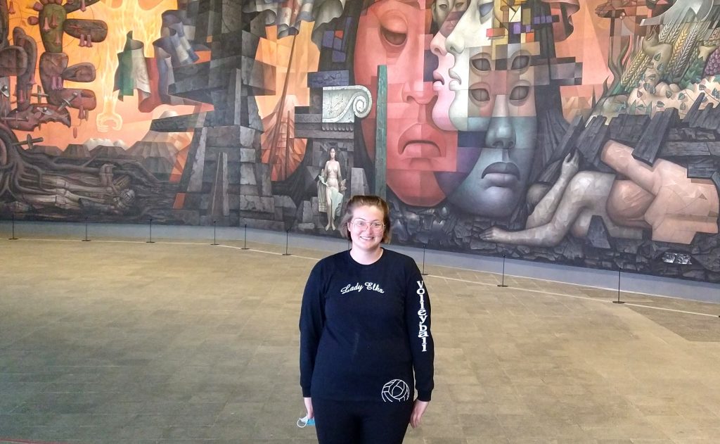 Janelle Peña stands in front of mural in Chile