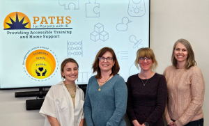 group photo of PATHS team standing in front of a presentation screen with a PATHS graphic