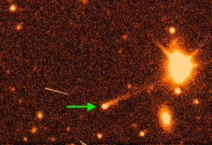 Orange and black image of solar system objects with an arrow pointing to a bright orb with a long tail--an active asteroid.